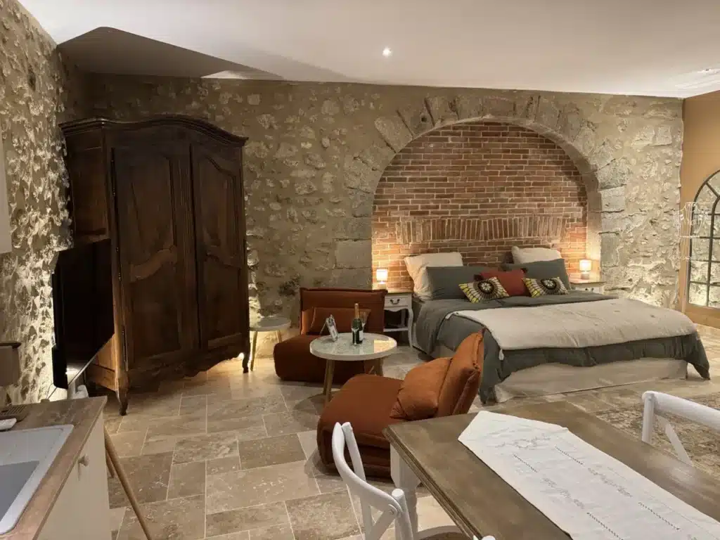 Chambre de la suite nuptiale des Granges Saint-Paul, lit King Size sous une arche en brique et murs en pierre